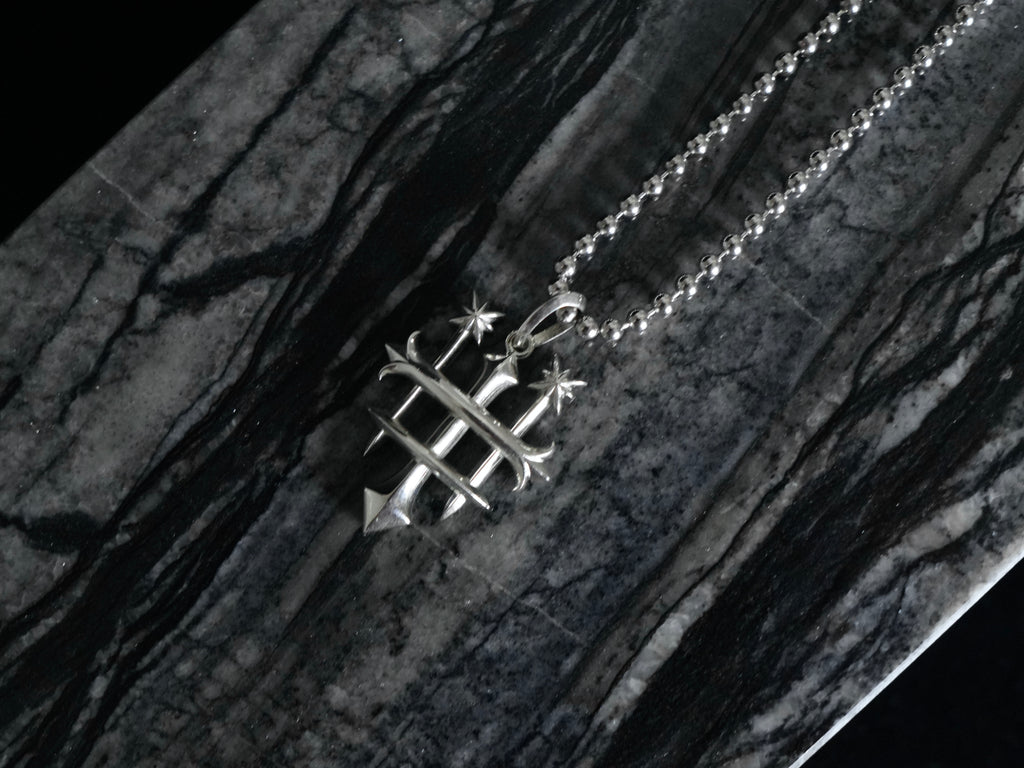 A silver pendant necklace featuring the Rusbaron Troika symbol, resting on a dark, polished black and gray marble surface.