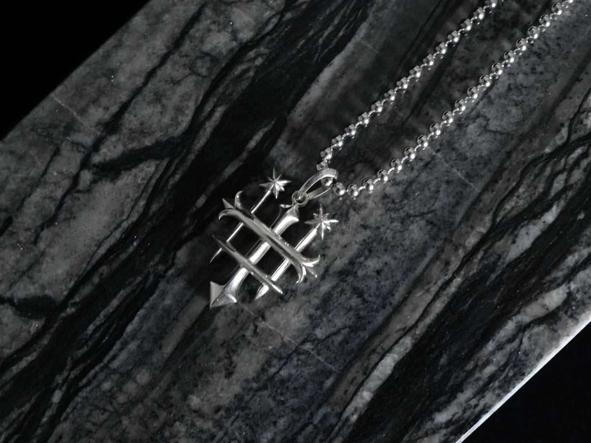A silver pendant necklace featuring the Rusbaron Troika symbol, resting on a dark, polished black and gray marble surface.
