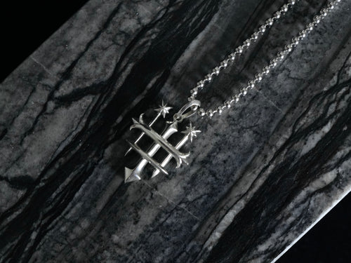 A silver pendant necklace featuring the Rusbaron Troika symbol, resting on a dark, polished black and gray marble surface.